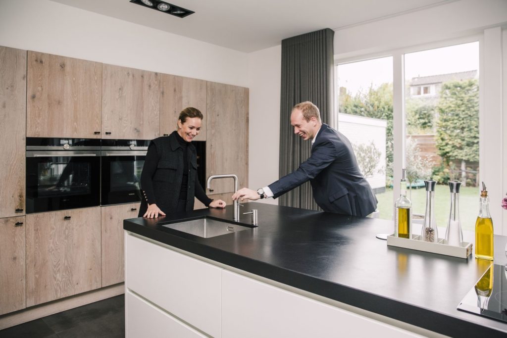 Twee mensen bekijken een moderne keuken met eiland.