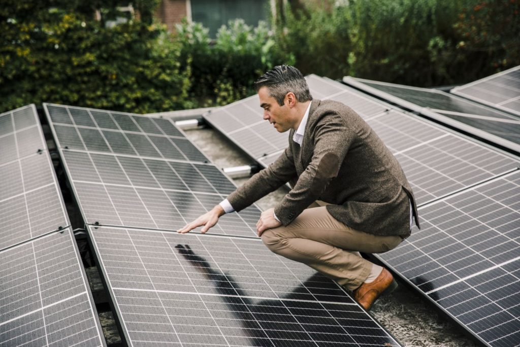 Man inspecteert zonnepanelen op dak.