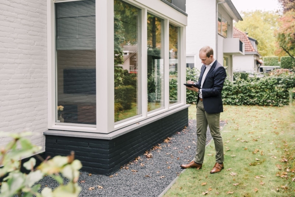 Man inspecteert woning exterieur met notitieblok