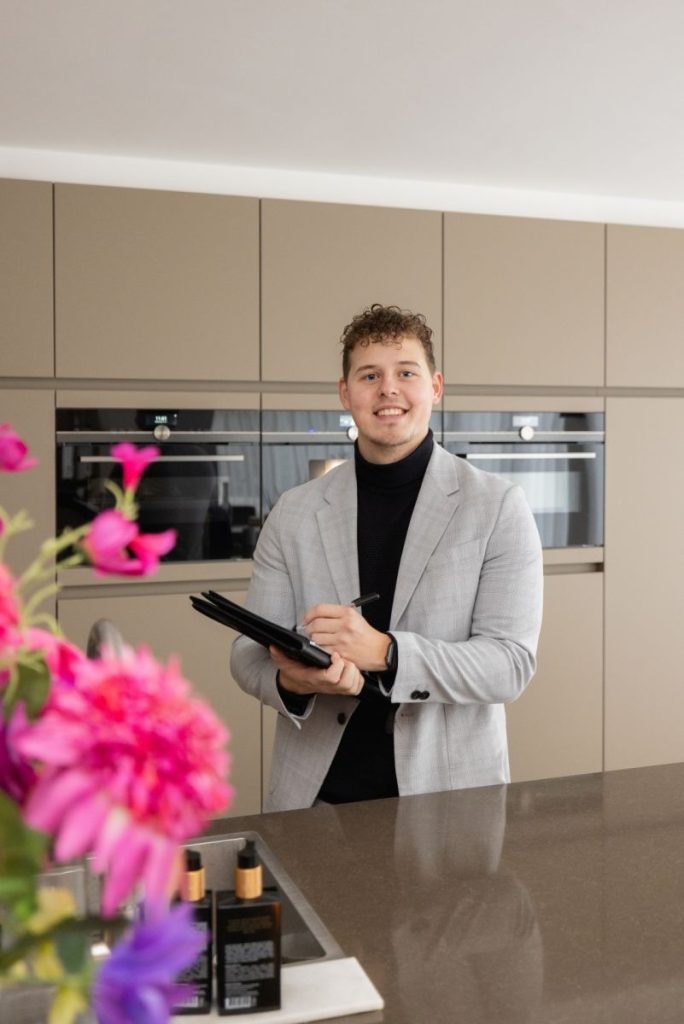 Man in moderne keuken met notitieblok glimlachend.