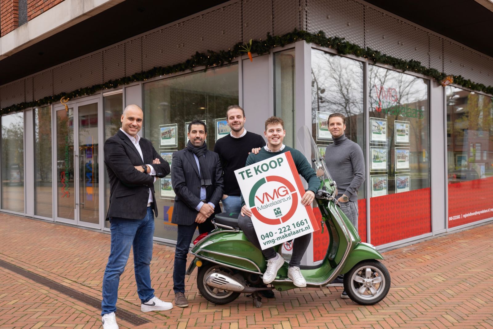 Vijf mannen voor verkoopkantoor met te koop bord.