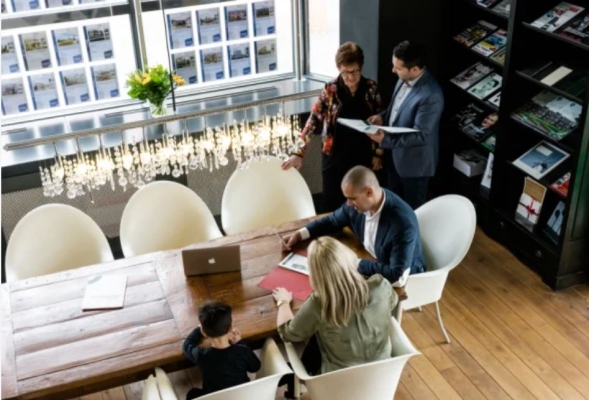 Vergadering in moderne kantoorruimte met laptops.