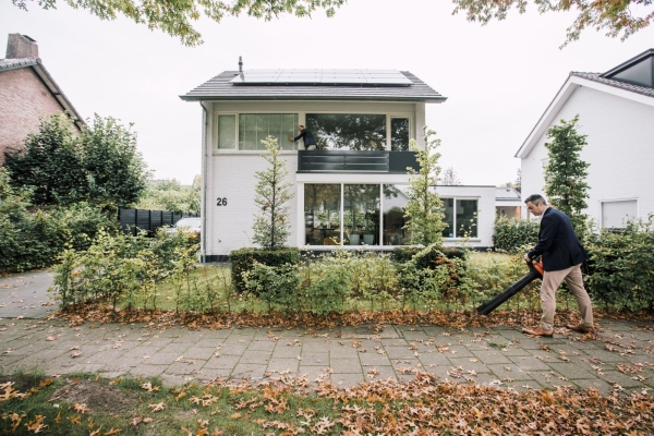 Twee mensen bij huis, één met bladblazer.