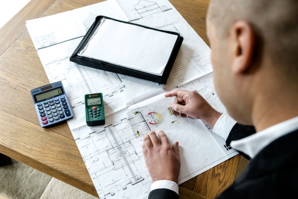 Man werkt aan bouwtekening met rekenmachine