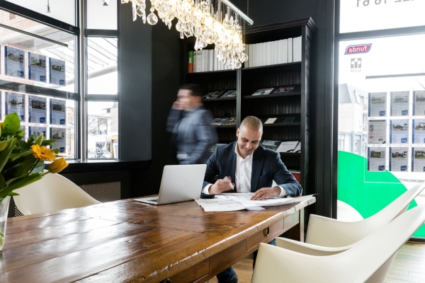 Man aan bureau met laptop en documenten.