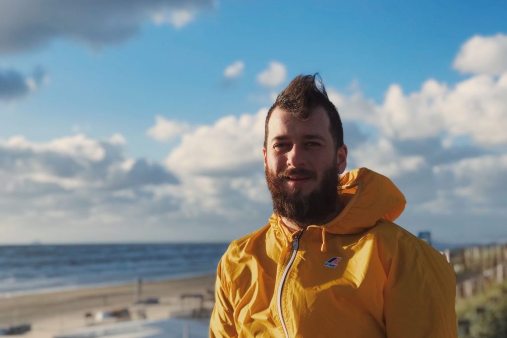 Man in gele jas bij het strand
