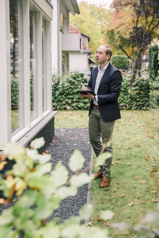Man inspecteert huis buiten in tuin