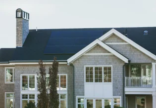 Grijze villa met zonnepanelen en schoorsteen.